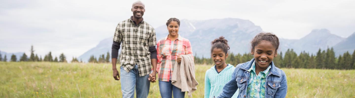 happy parents with kids walking through green pastures